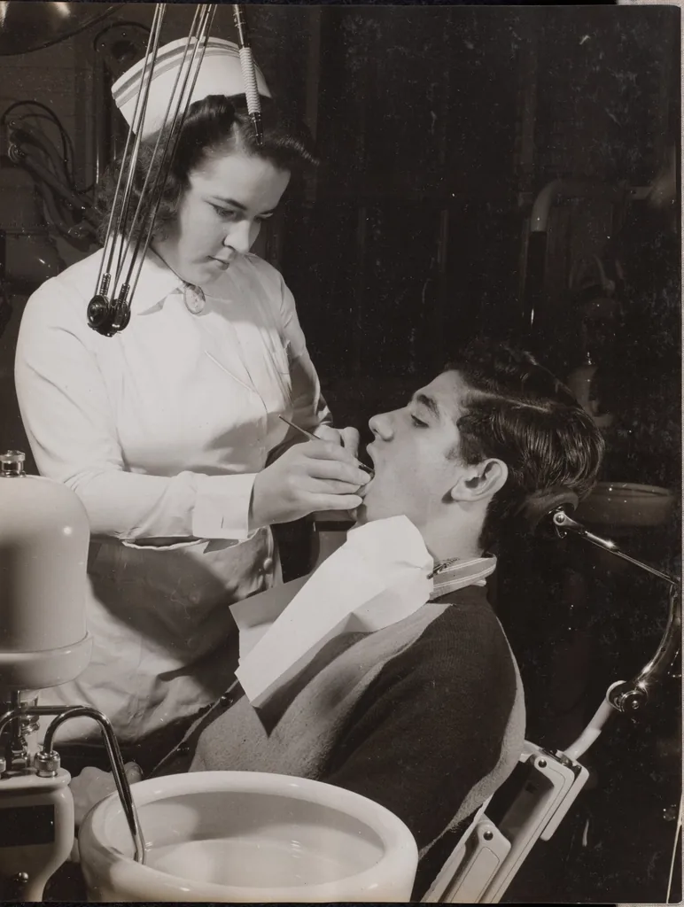 A dental hygienist examining a patient in the exam chair