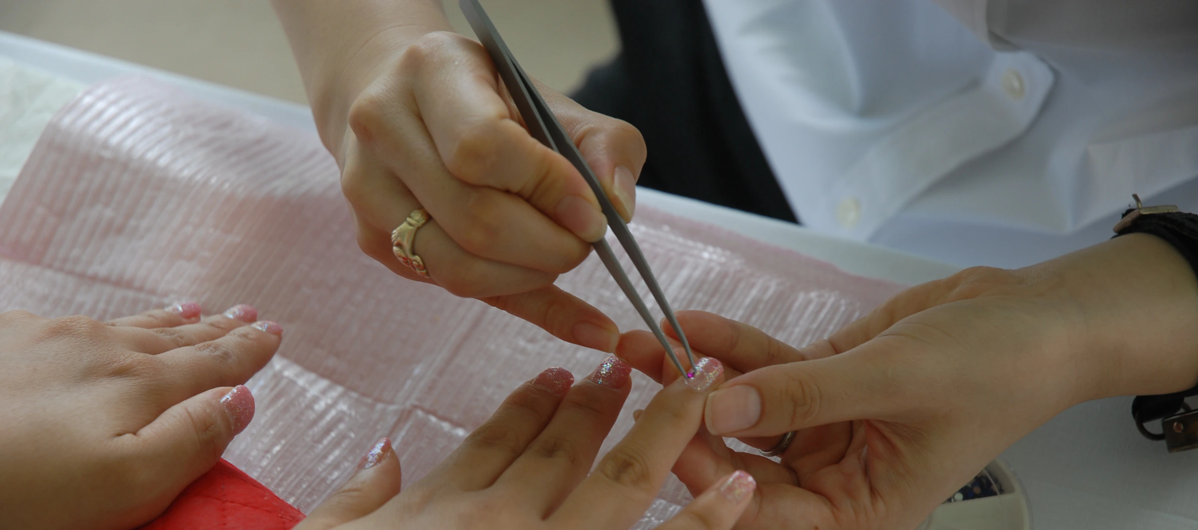 A nail technician applying decorative nail art during a manicure